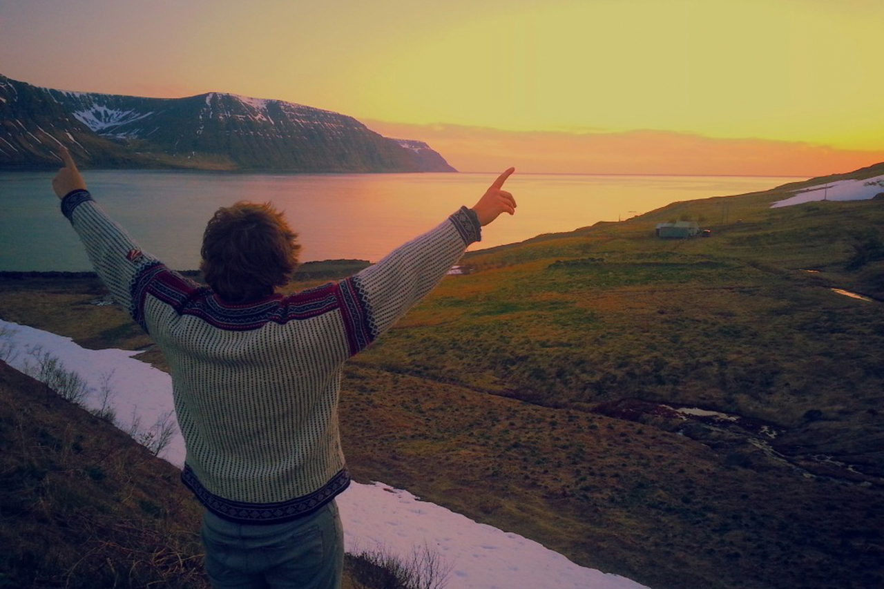 person with outstreched arms overlooking water and mountains