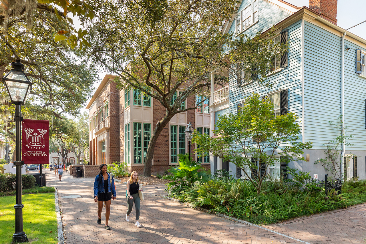 students walk past buildings on the college of charleston campus