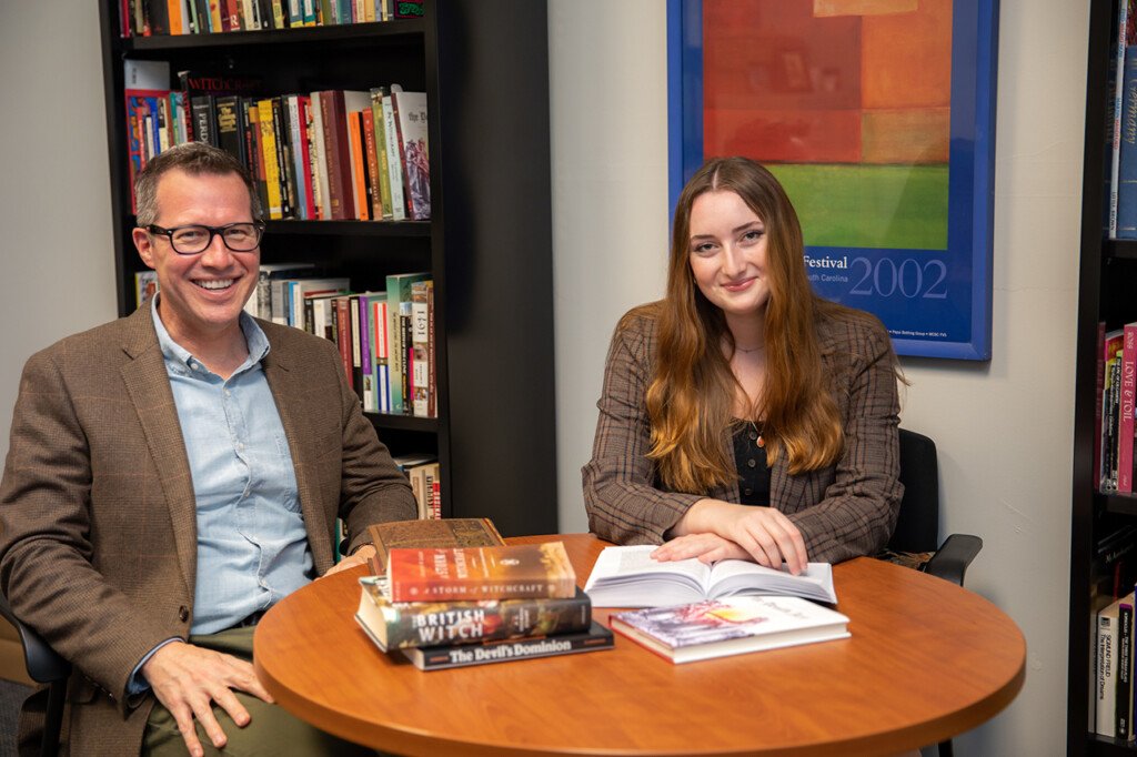 man and woman sitting at a table with books on it