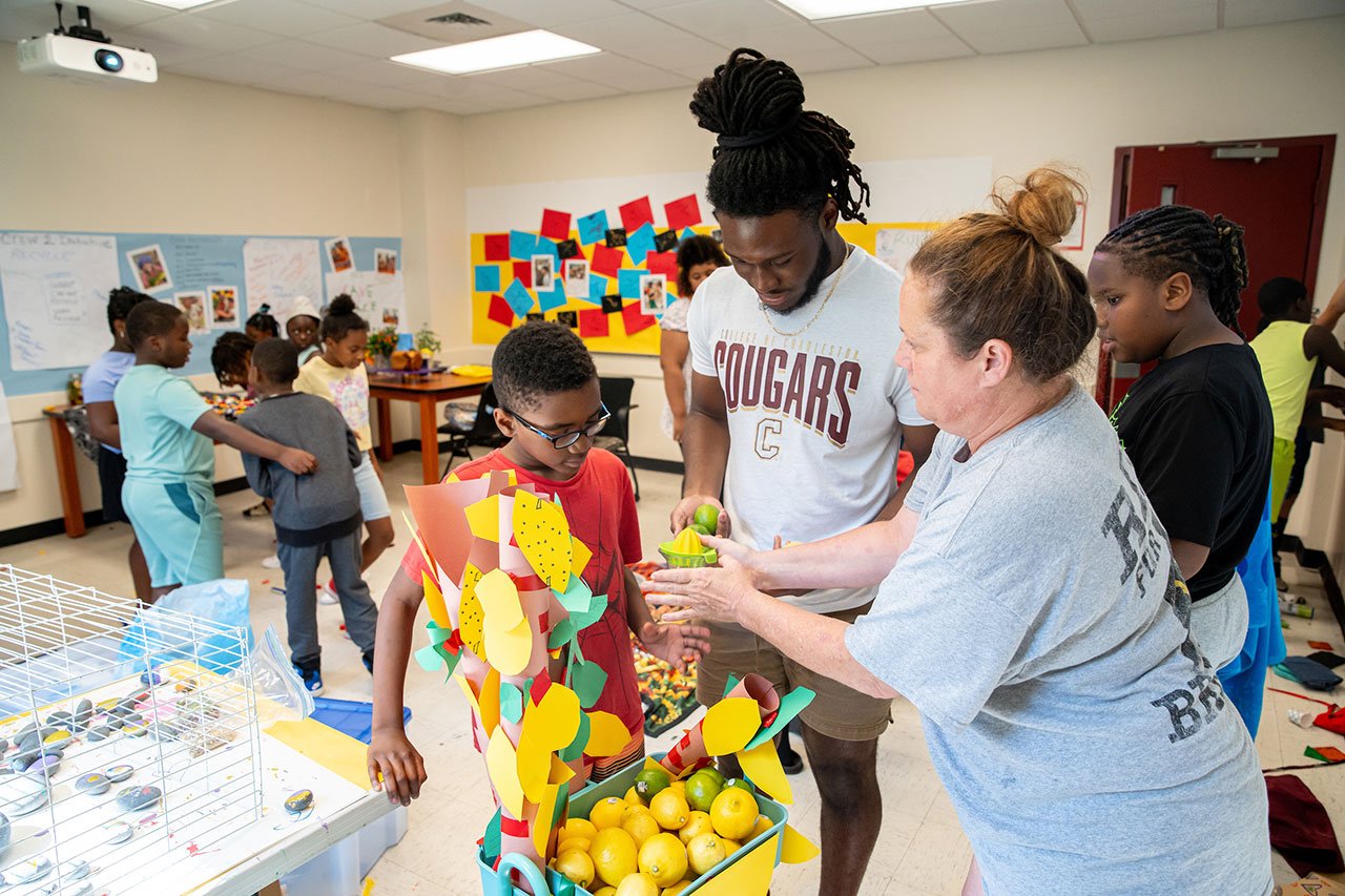 two teachers work with a student on a lemon and lime tree craft