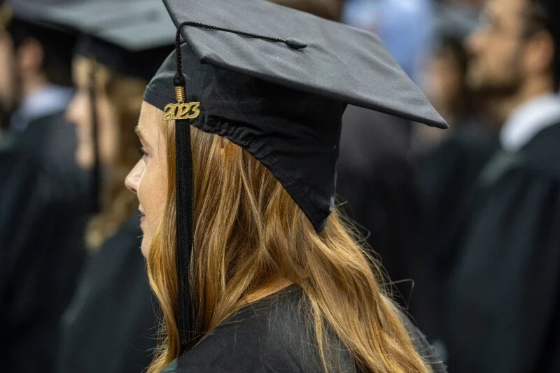 Graduates standing and dressed in graduation cap and gowns.