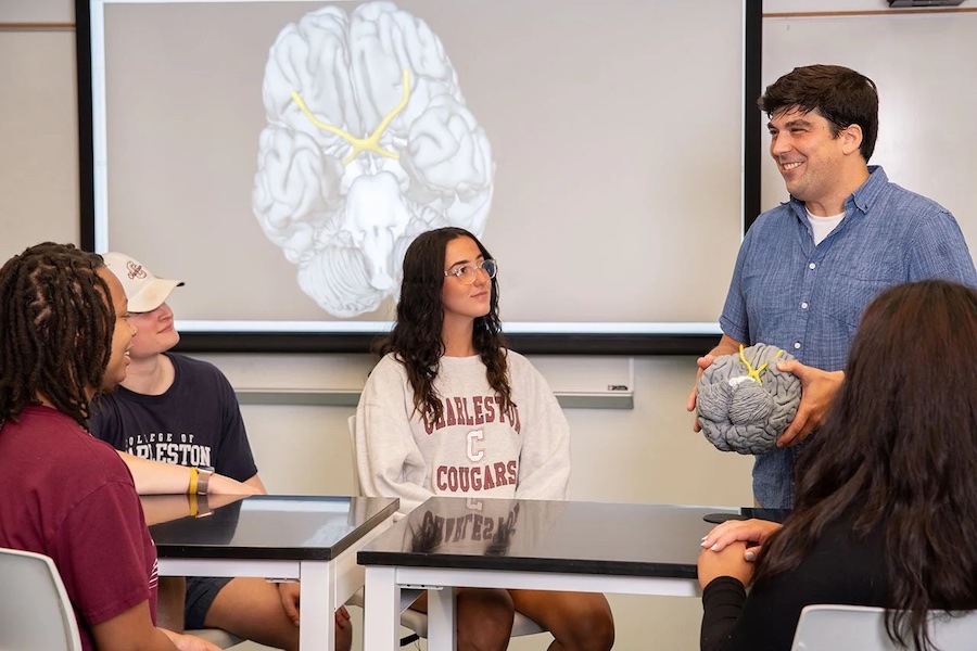 Professor Handy holding a replica of a human brain while talking to students.