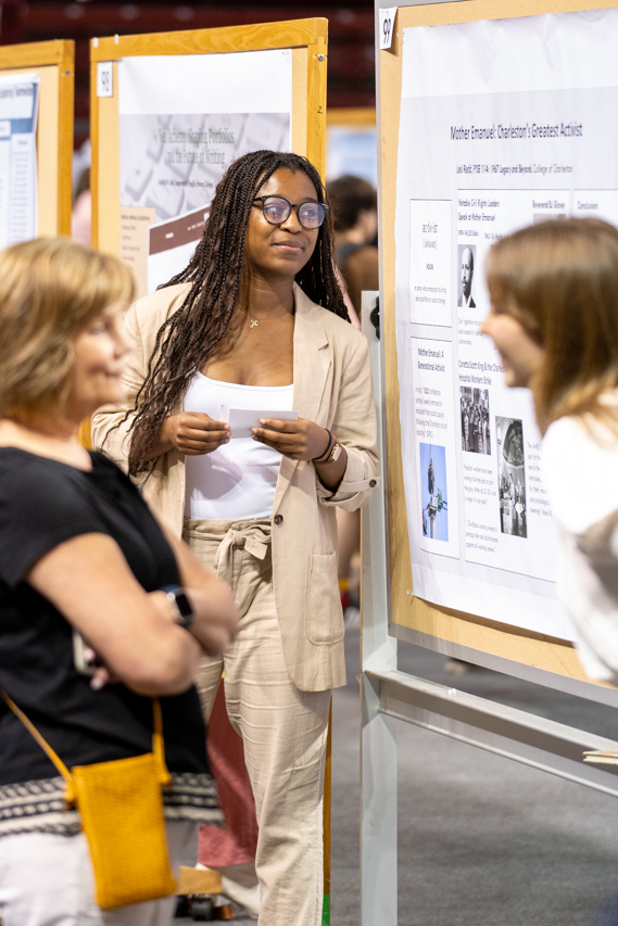 Student stands by research poster at 2024 EXPO