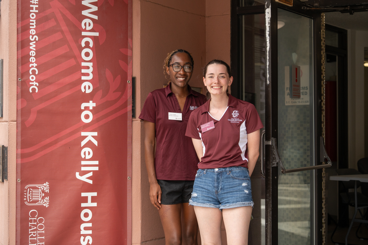 staff pose outside of Kelly hall on move in day