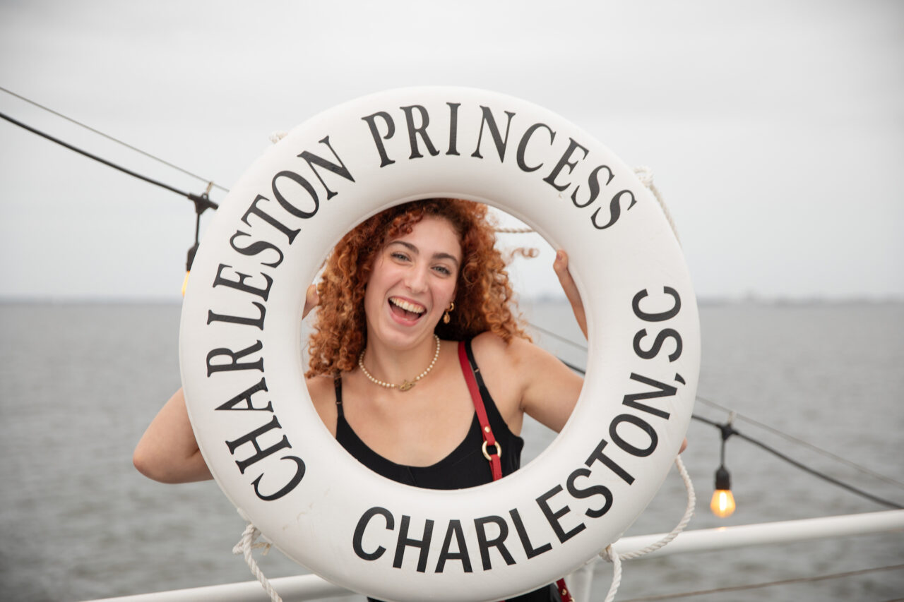 Student poses with liferaft at CAB Harbor Cruise.