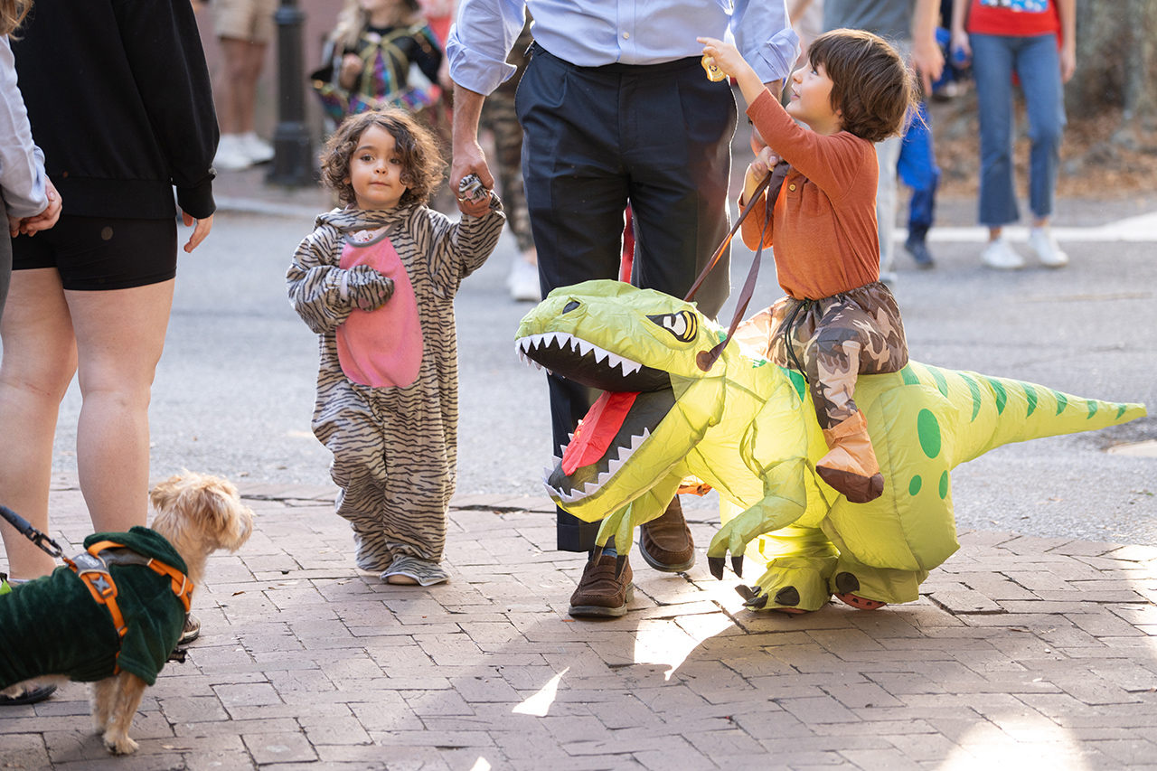 dog looks at kid in dinosaur costume