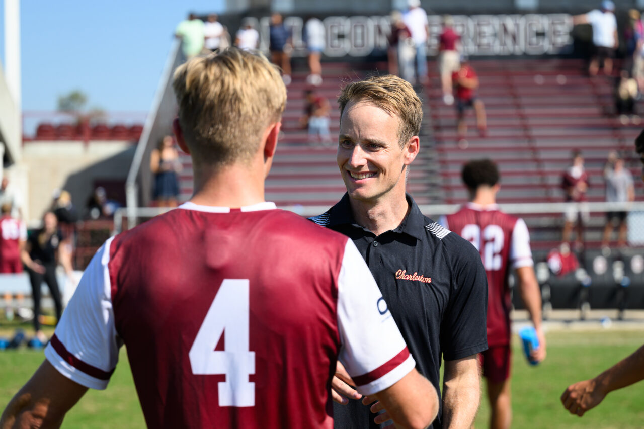 Coach with player at CofC Men's soccer game