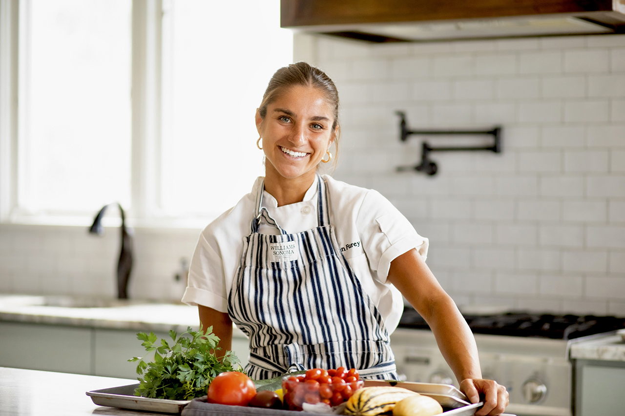 A woman in an apron smiling at the camera.