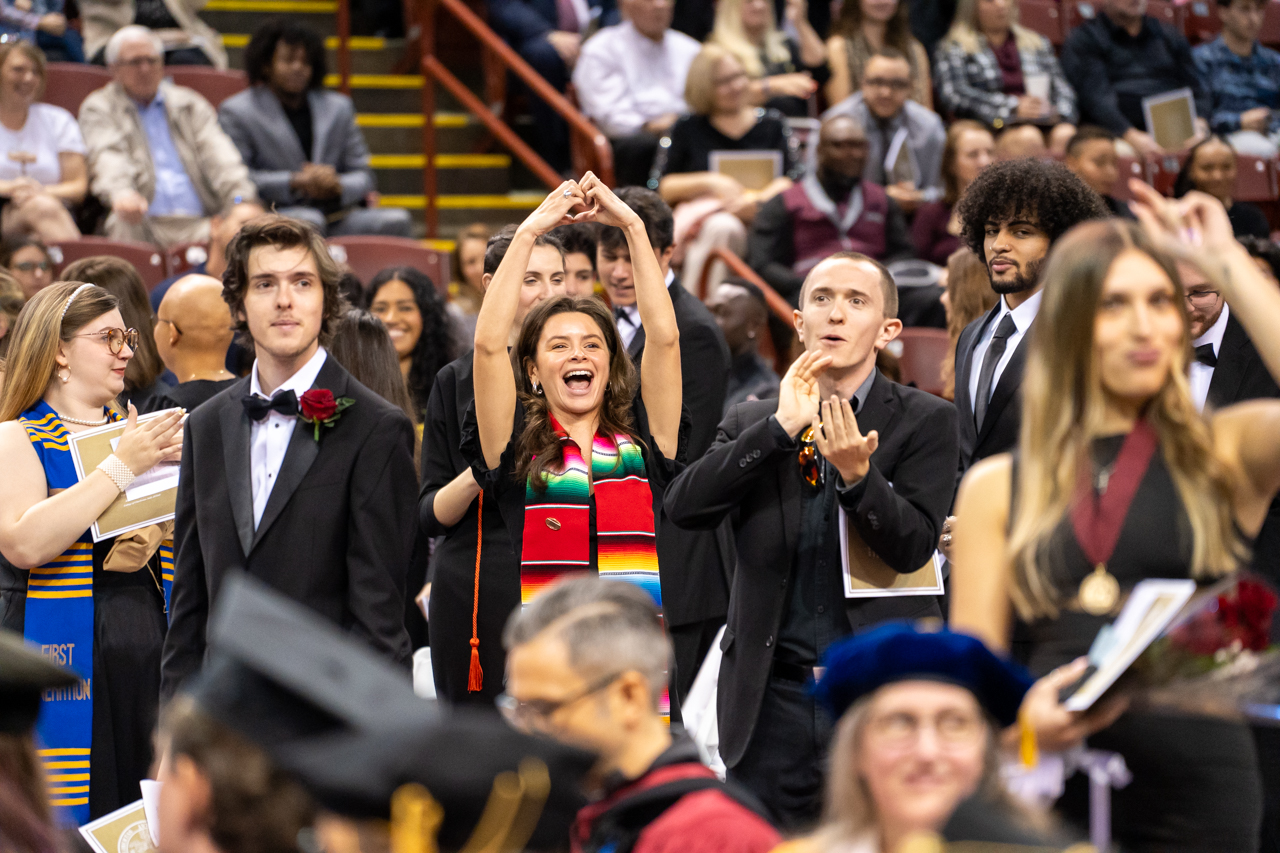 graduate makes heart shape at winter graduation at the College of Charleston