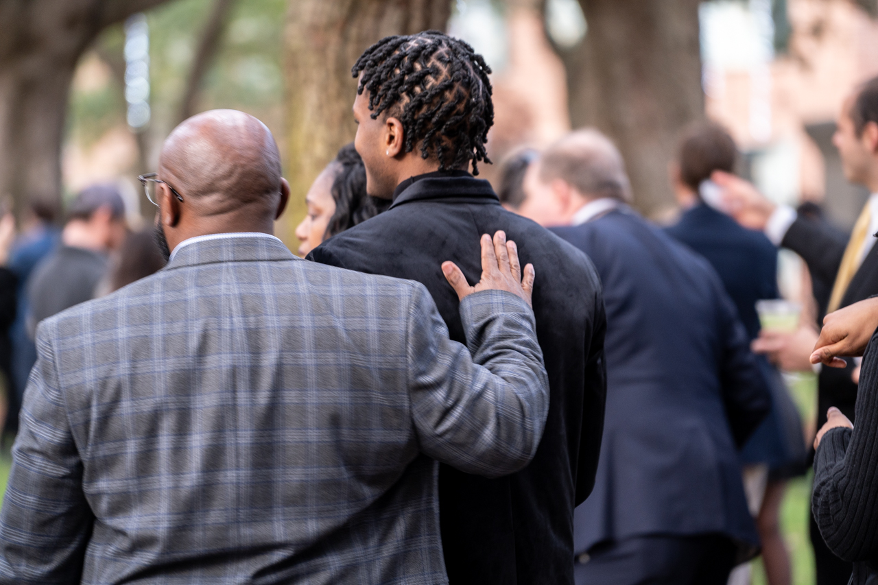 father puts his hand on son in proud moment after graduation 