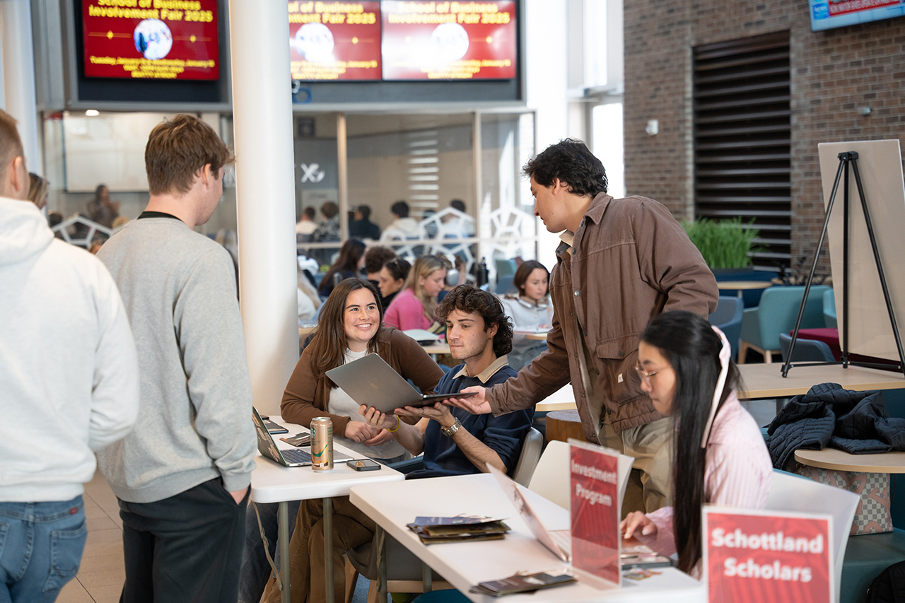 students gather around to discuss content at school of business involvement fair 