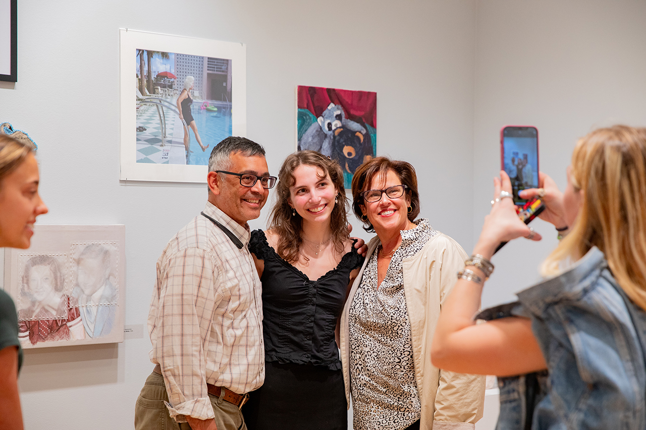 taking photos with artwork at Halsey's Young Contemporaries Exhibit. Recognized students are joined by their friends and families as they look over awarded art works.