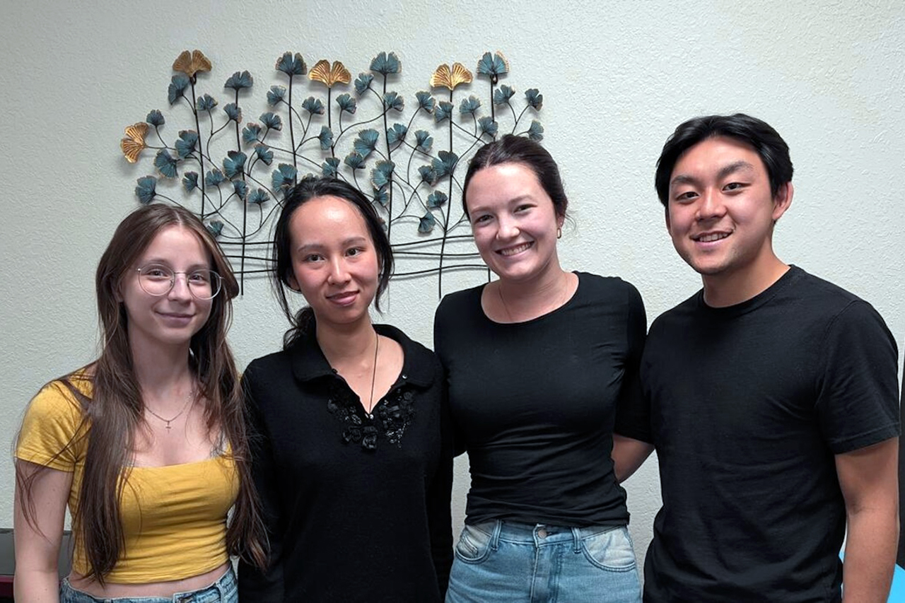 Four undergraduate students smile