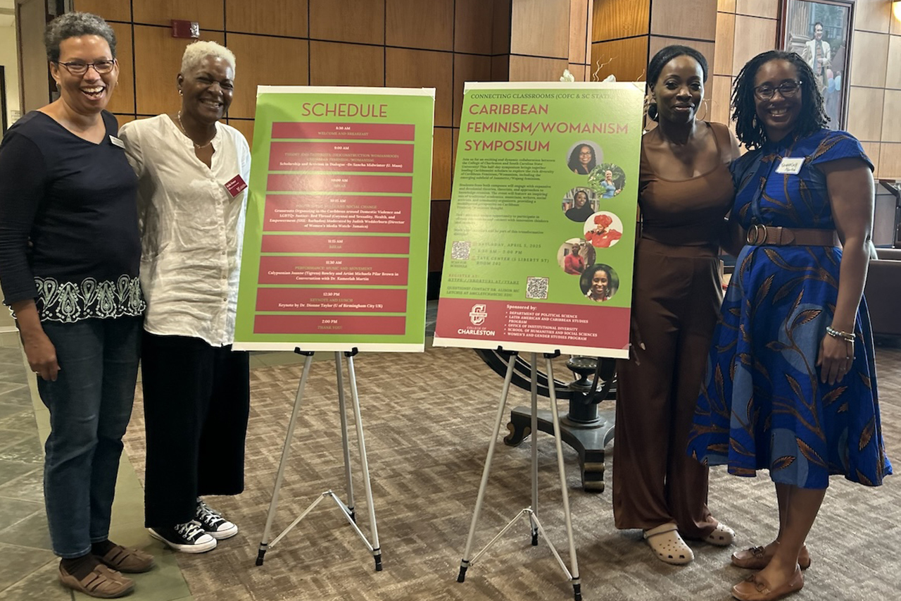 four higher education professors gather around posters in a conference room