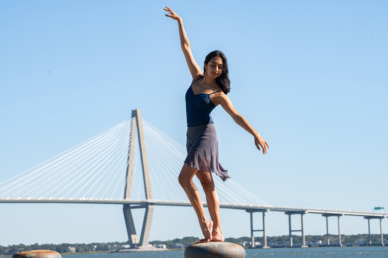 woman dancing in front of bridge and blue skies