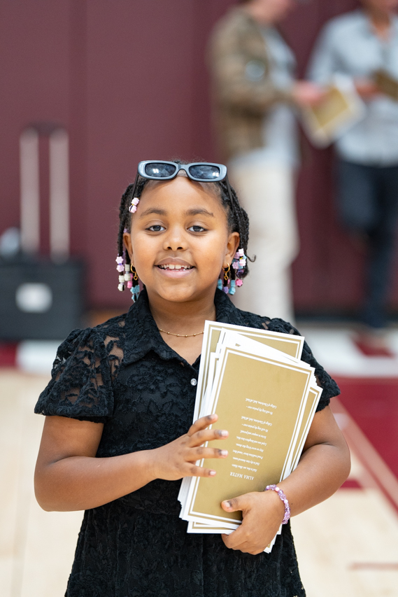 young girl holds graduation booklets