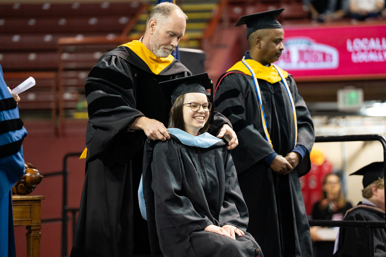graduate student gets a sash during commencment 