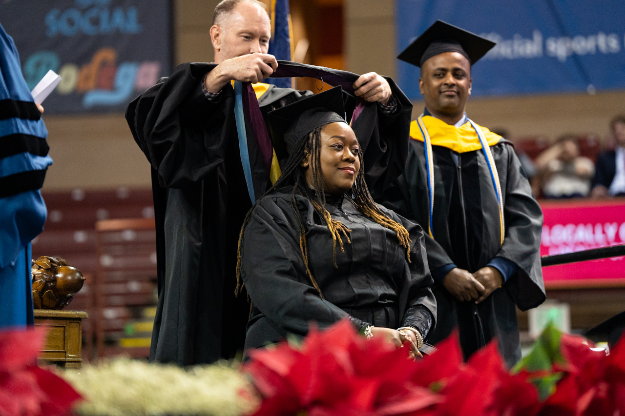 graduate student shows pride as she sits to receive her sash