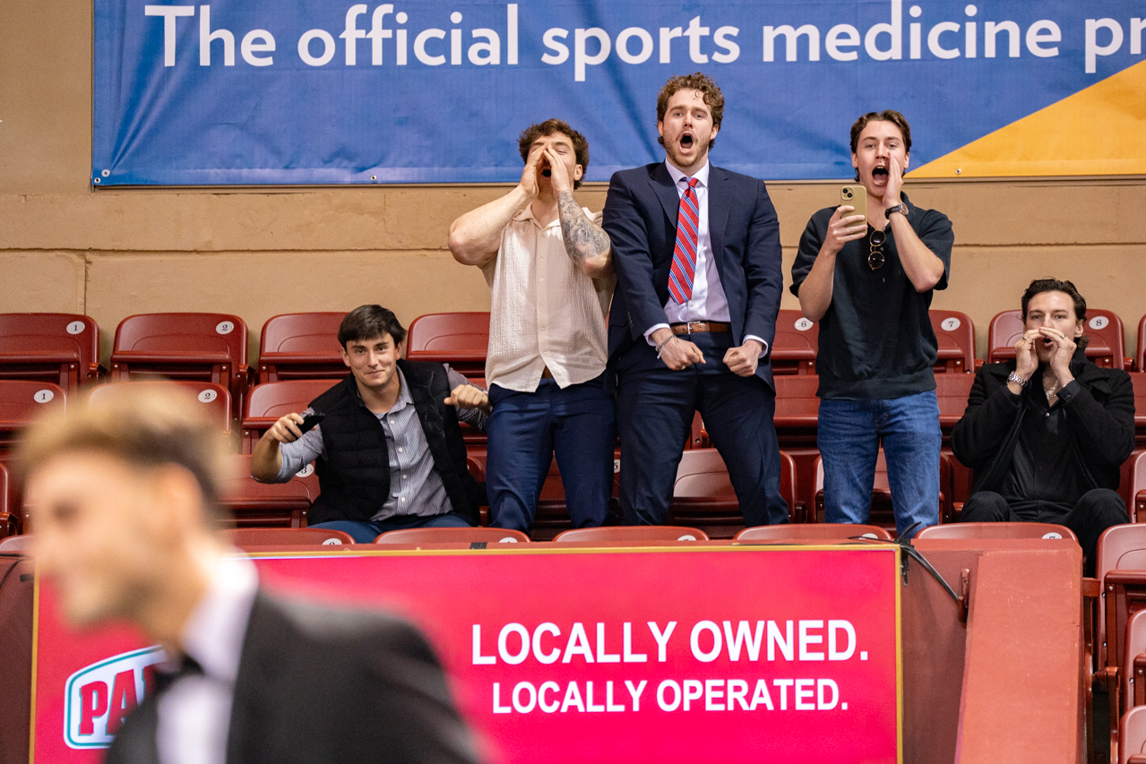 male attendies yell for their friend as they walk the stage