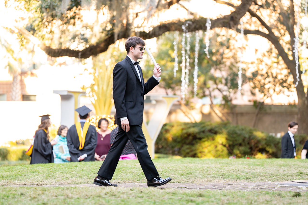 from another angle a male student walks the cistern diploma in hand