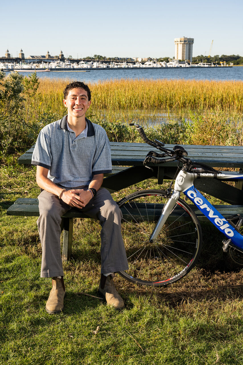 Liam Desjardins sits on bench in front of marsh