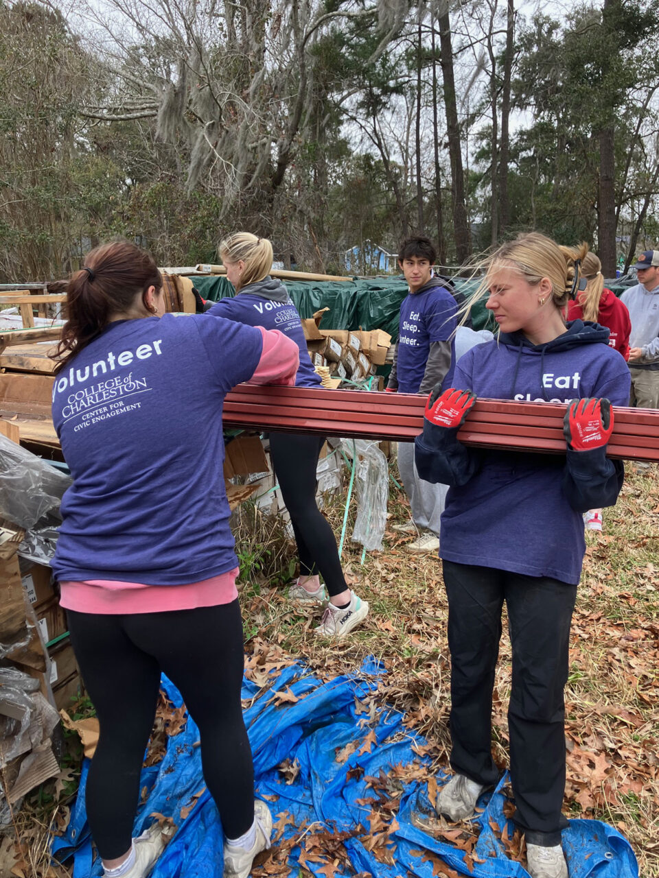 two students hold lumber at habitat for humanity build 