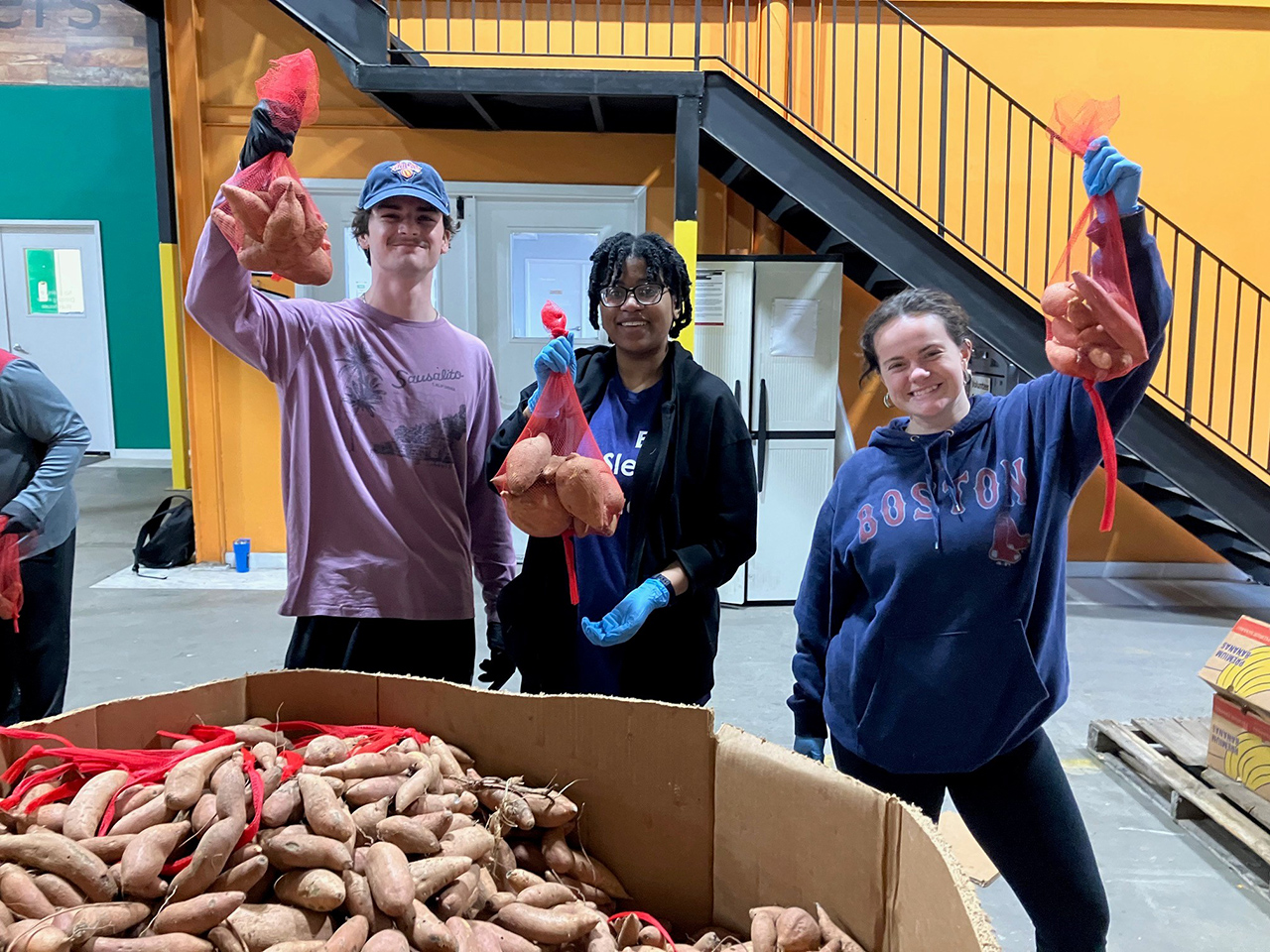 Three Students hold up potatoes 