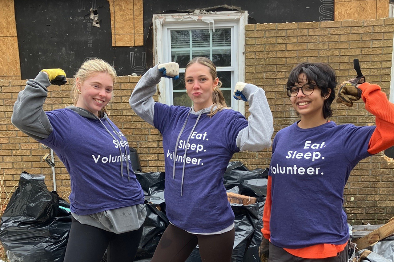 Three female students show their biceps for fun in front of the camera 