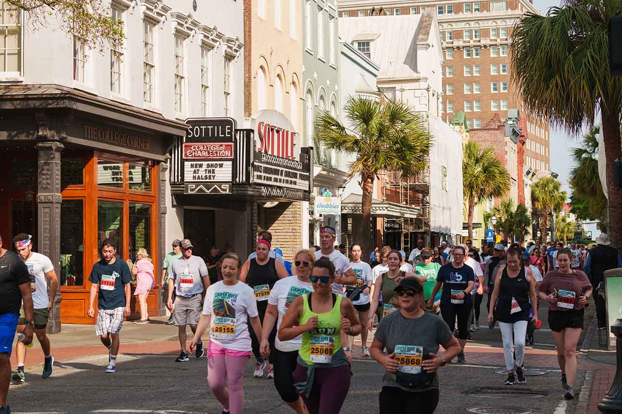 people running down King Street crossing George Street for Cooper River Bridge Run