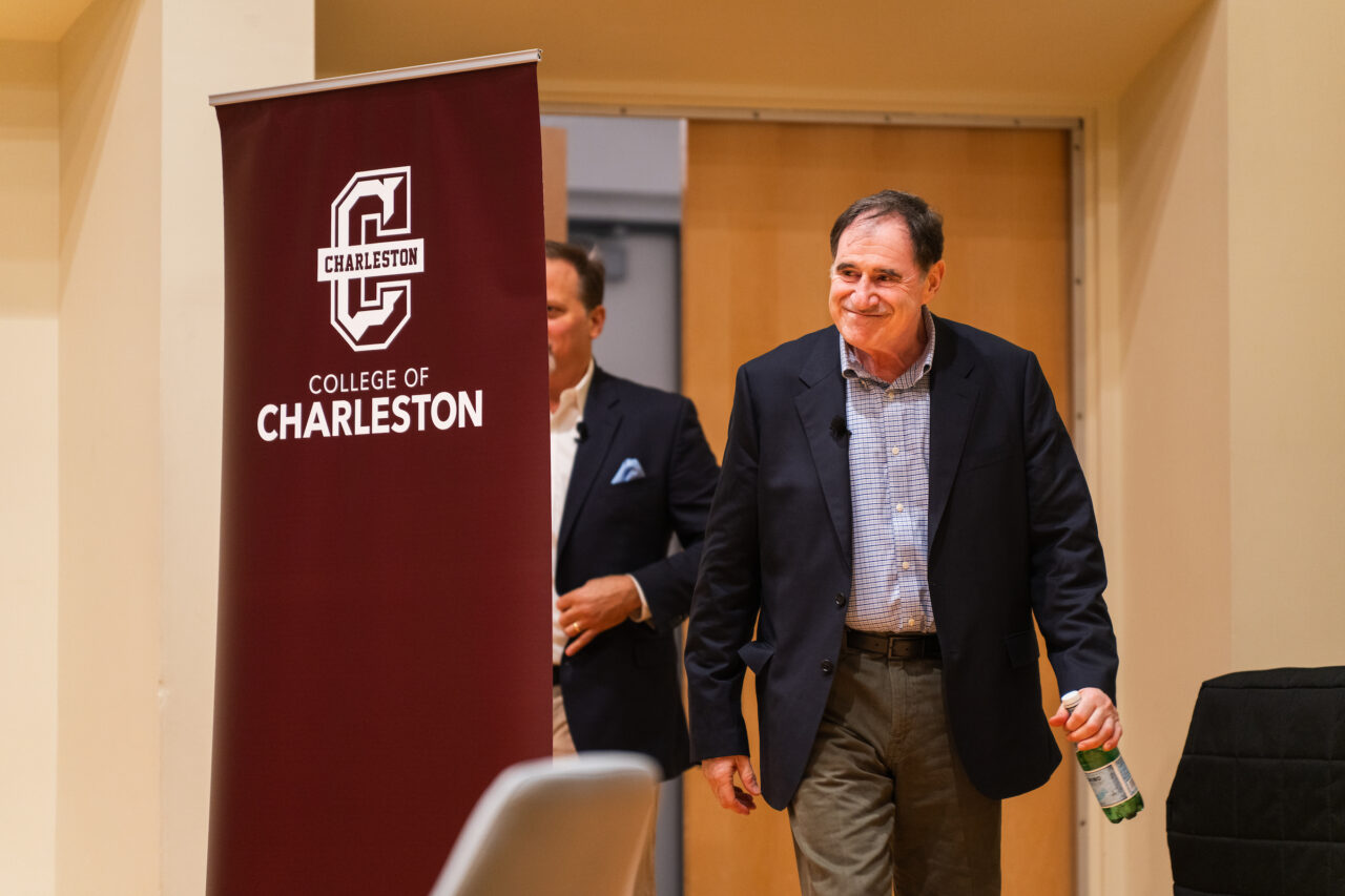 Richard Kind walks into auditorium with College of Charleston branding 