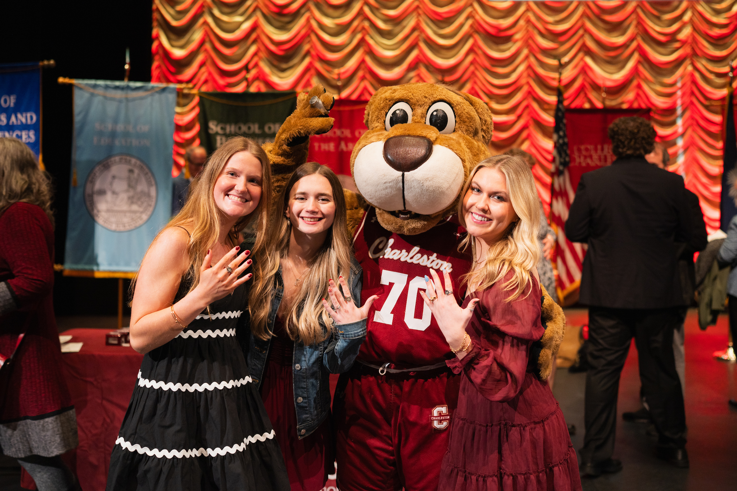 women students pose with Clyde, showing their CofC rings