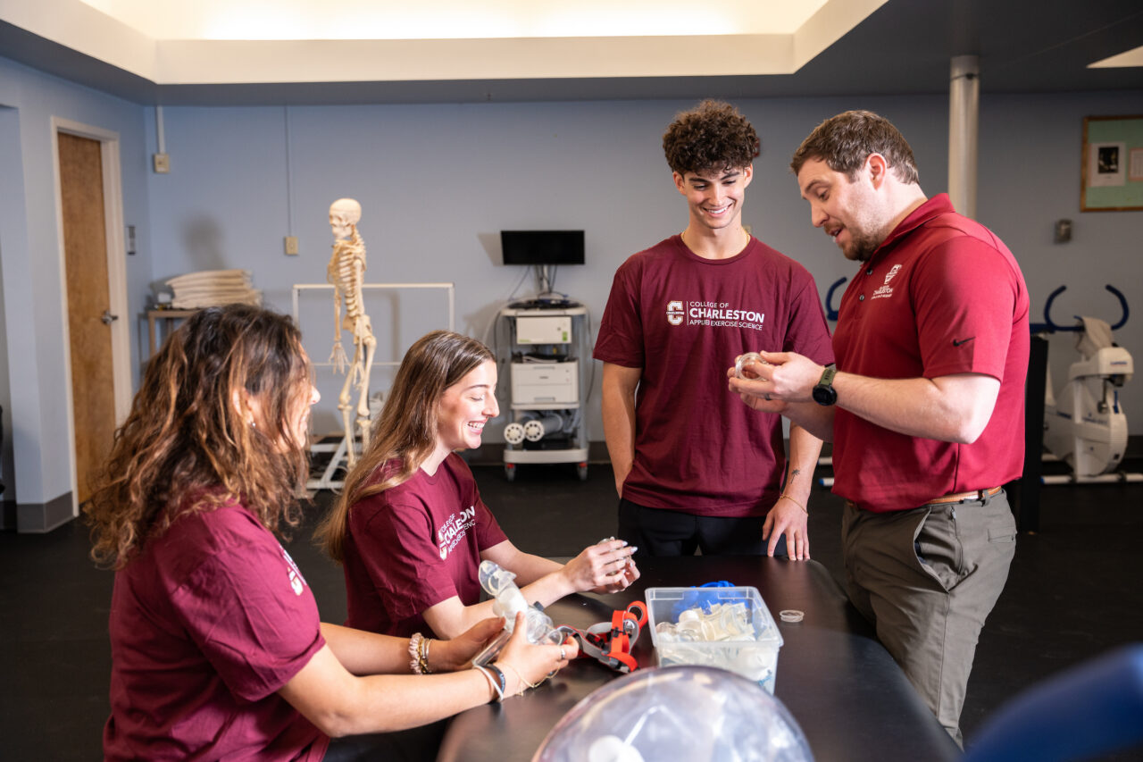 students and faculty gather around respiratory equipment