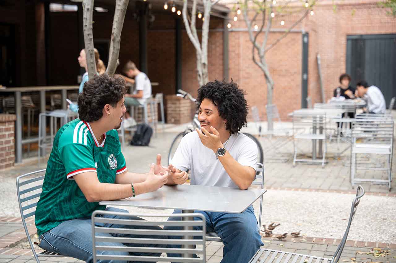 Manny Contreras-Ramirez and Jalen Evans sit at an empty table outside