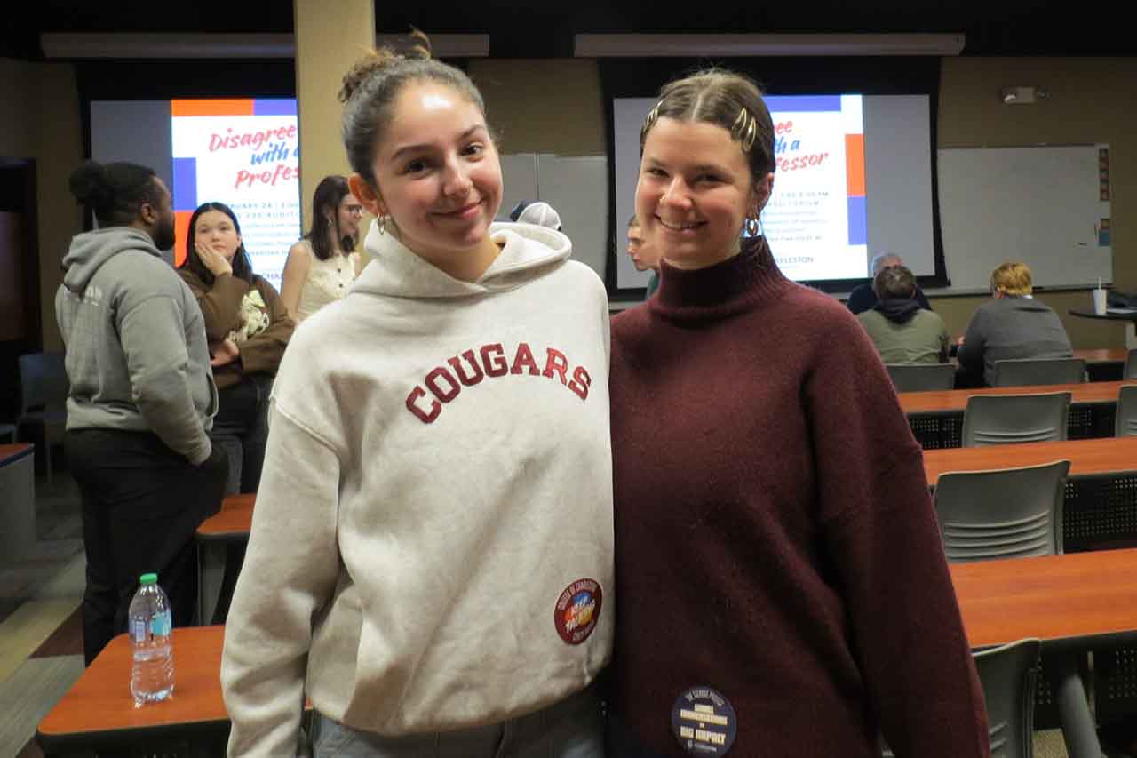 two people smiling at the camera in the back of a classroom