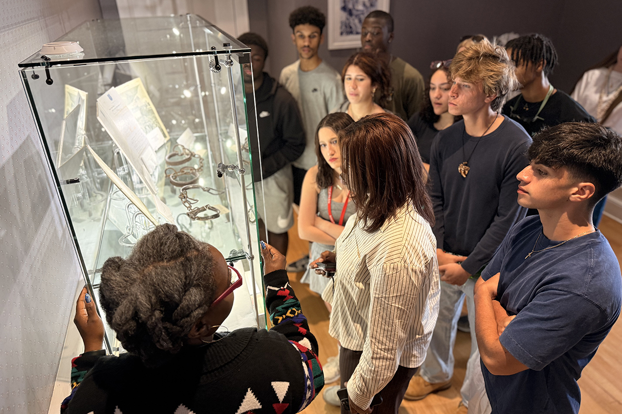 Tamara Butler explain  historical artifacts displayed in museum cases at the Avery Research Center.