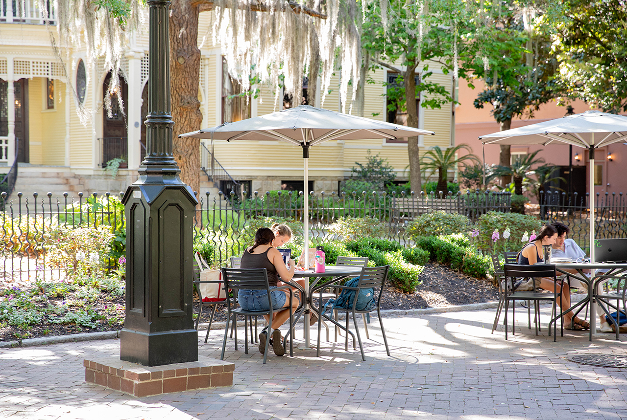 students sit at tables outside in the greenway