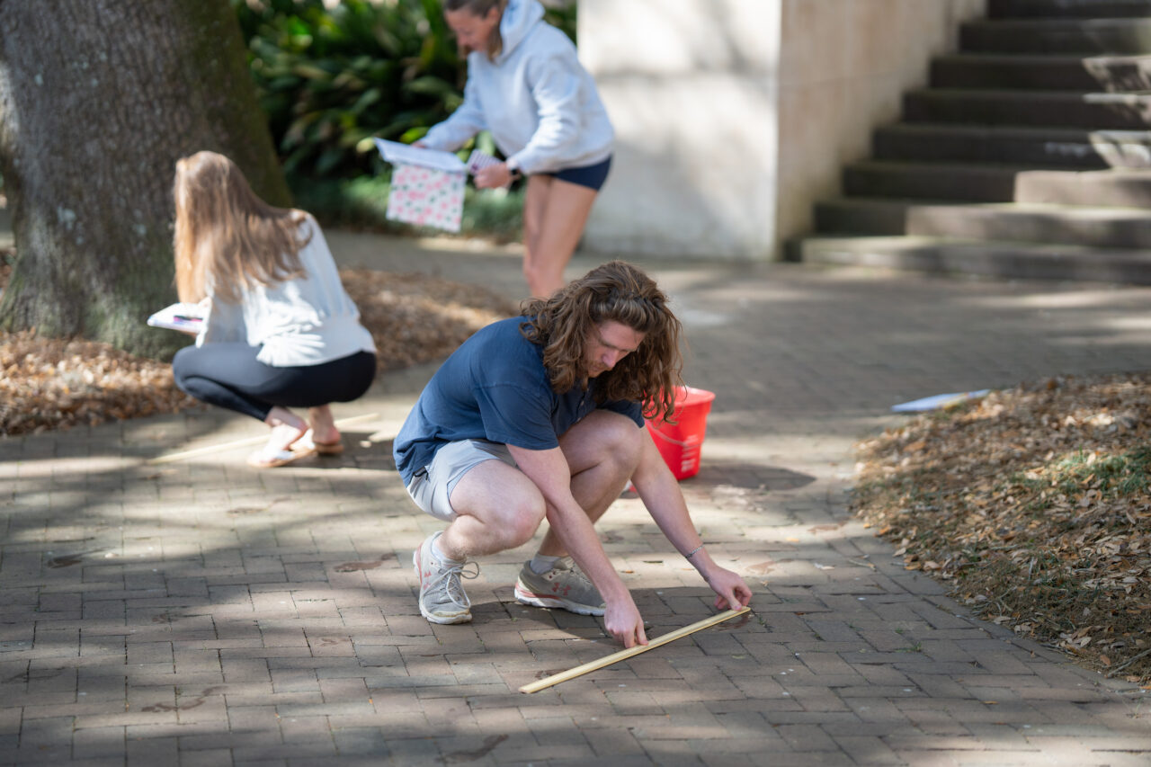 student takes measurements on walkway