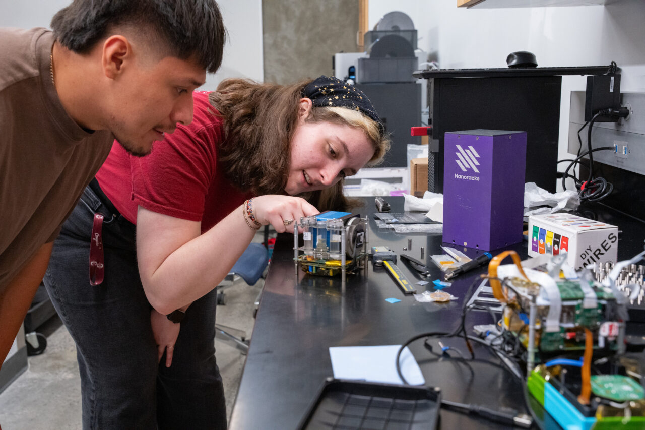 two students look at cube they helped build