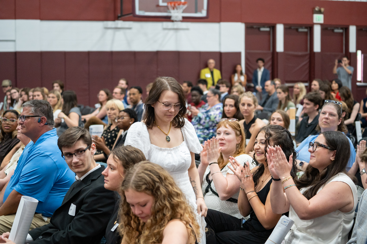 student walks to receive award as audience claps