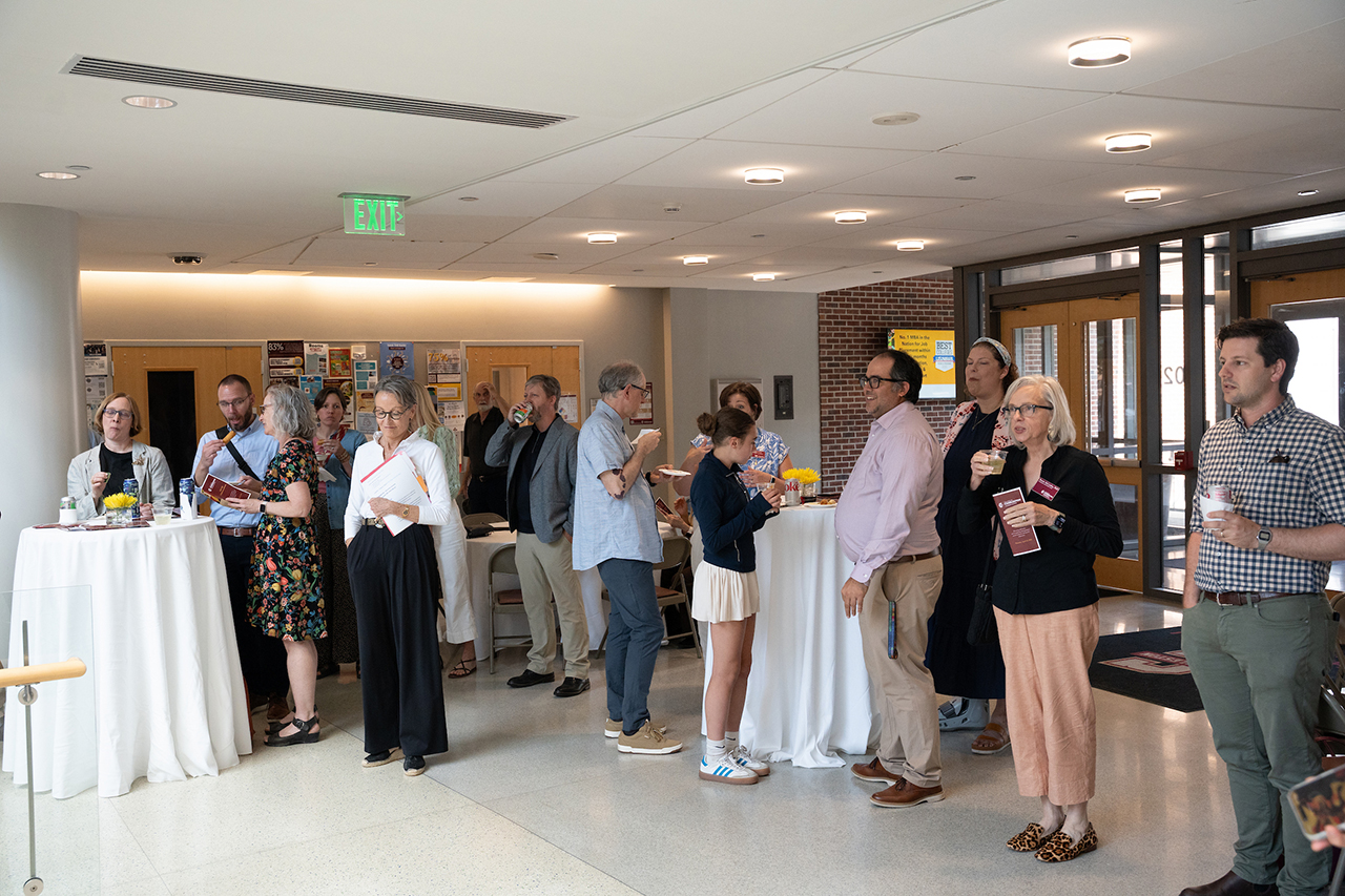 wide photo of a group of faculty members talking in lobby