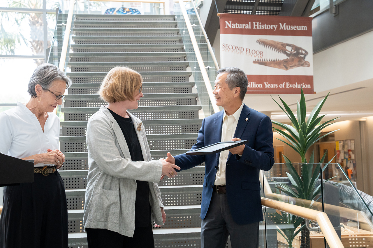 President Hsu shakes hands and presents award to faculty