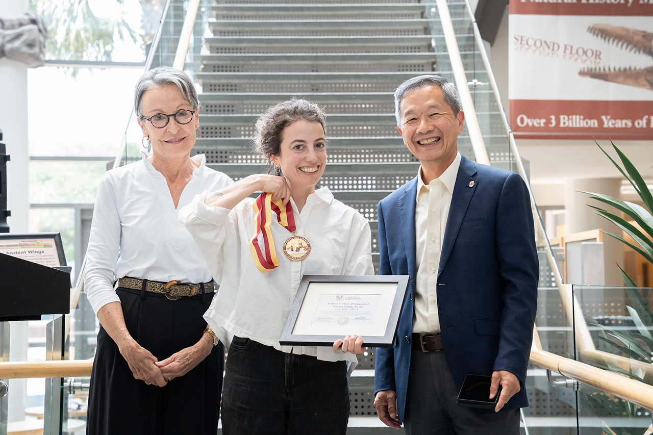 Woman holds up metal and plaque with president hsu and provost