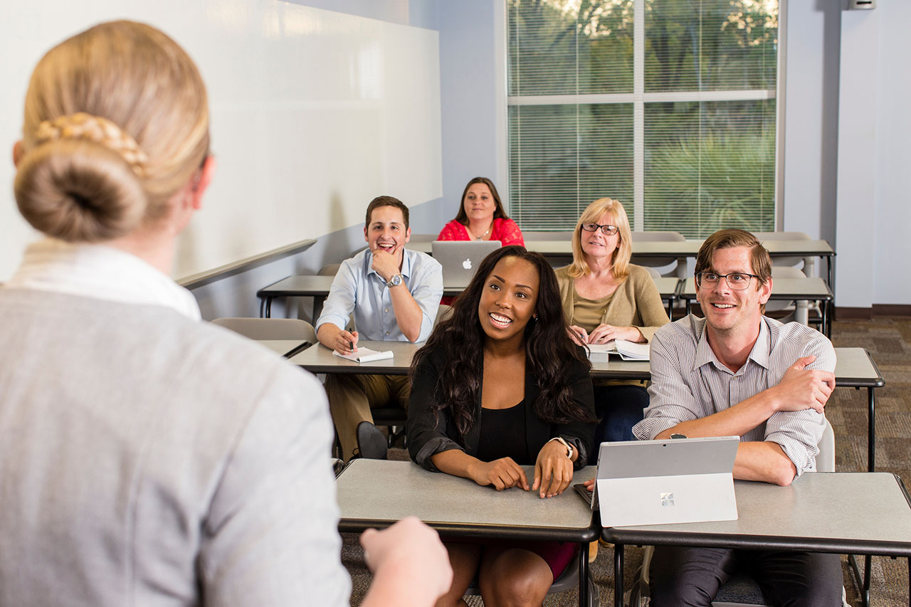 adult students sitting at desks listening to instructor
