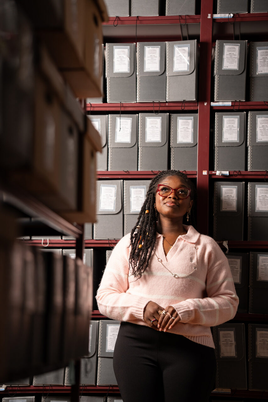 black woman looks up in archives with dramatic lighting
