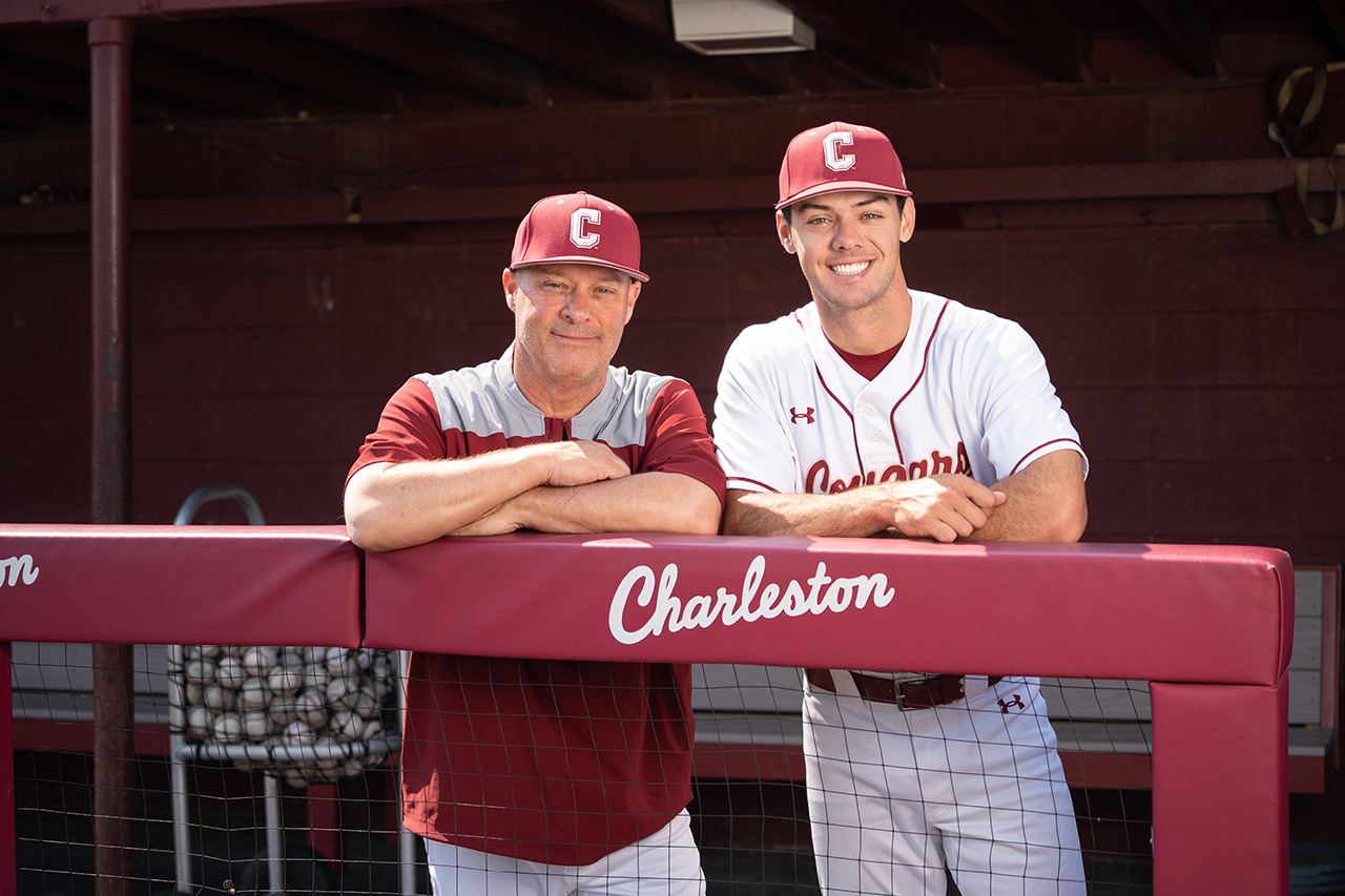 Baseball coach and player pose in dugout for photo