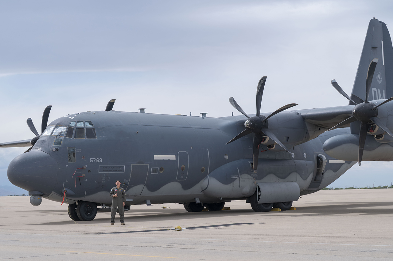 woman pilot stands in front of giant military plane