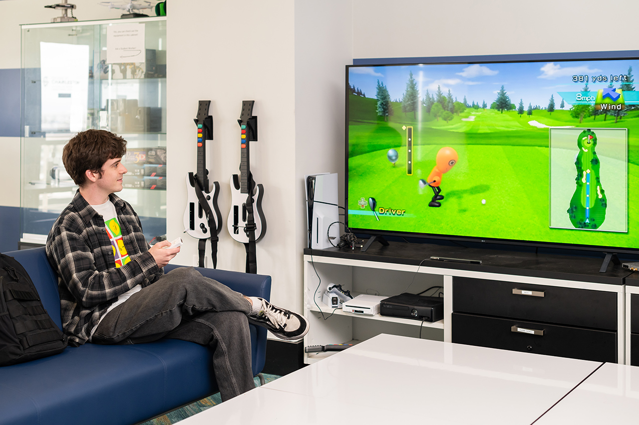 alumni plays Wii golf on a large tv