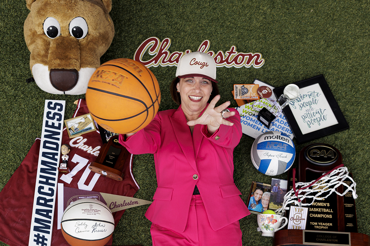 woman throws ball up towards the camera with College of Charleston swag around her