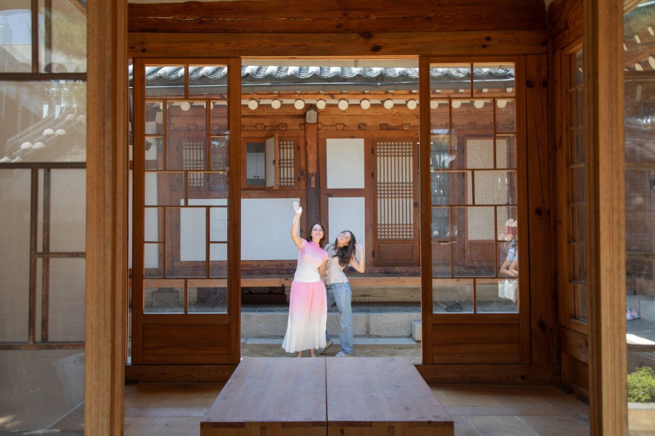 Students pose together through asian style window