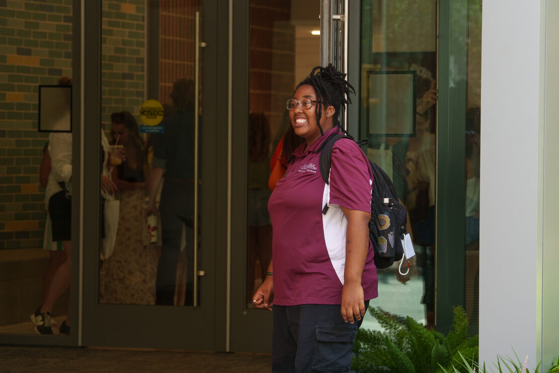 Student volunteer for the College of Charleston holds door and welcomes people